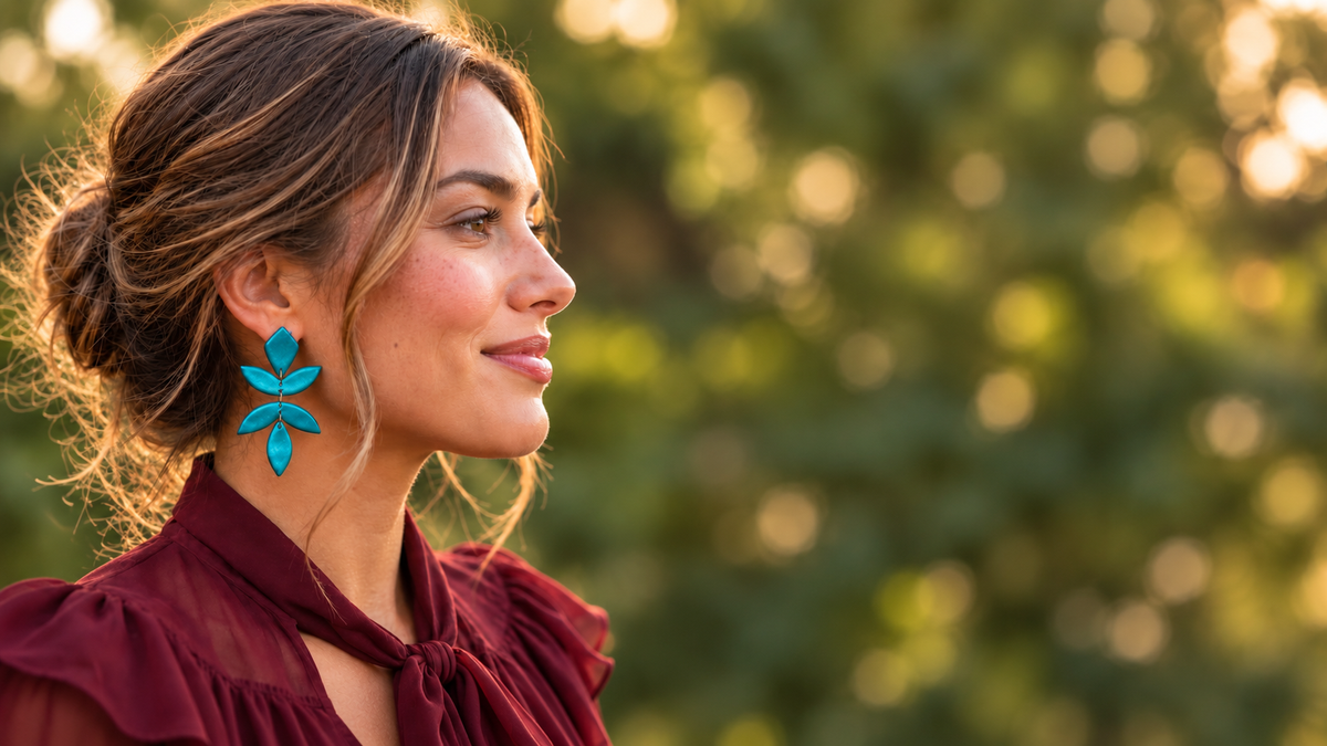 Turquoise statement oorbellen met bladmotief gedragen door vrouw in bordeauxrode blouse